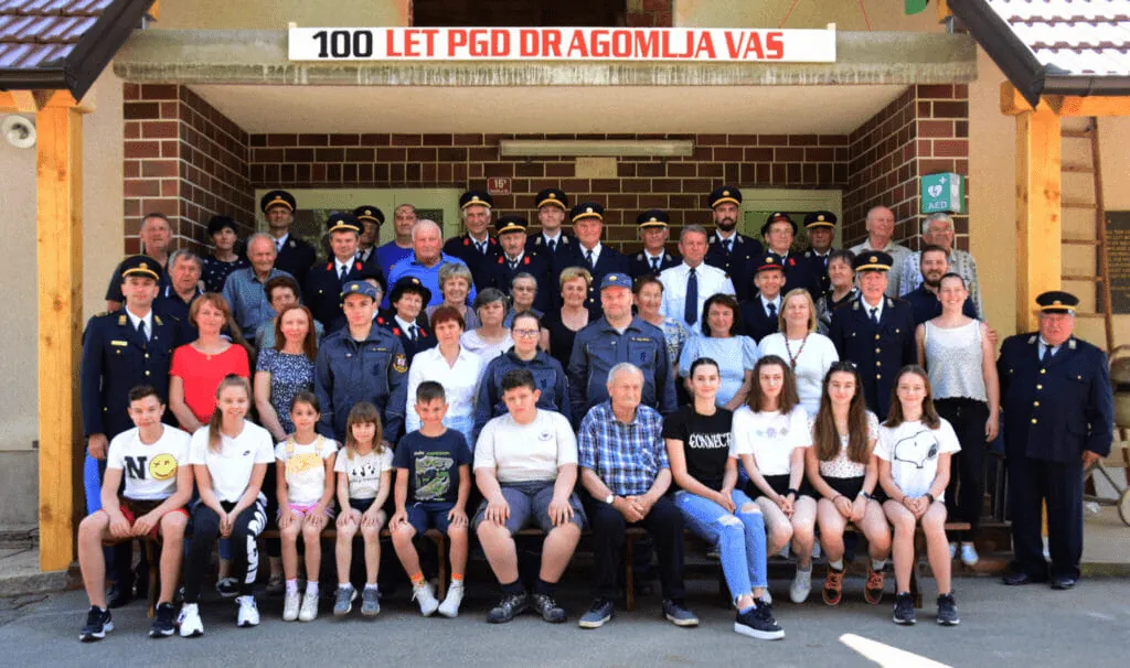 Skupinska fotografija članstva pred gasilskim domom ob 100. obletnici društva